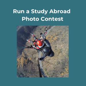 Run a Study Abroad Photo Contest. Aerial view of two people paragliding over a mountainous landscape.